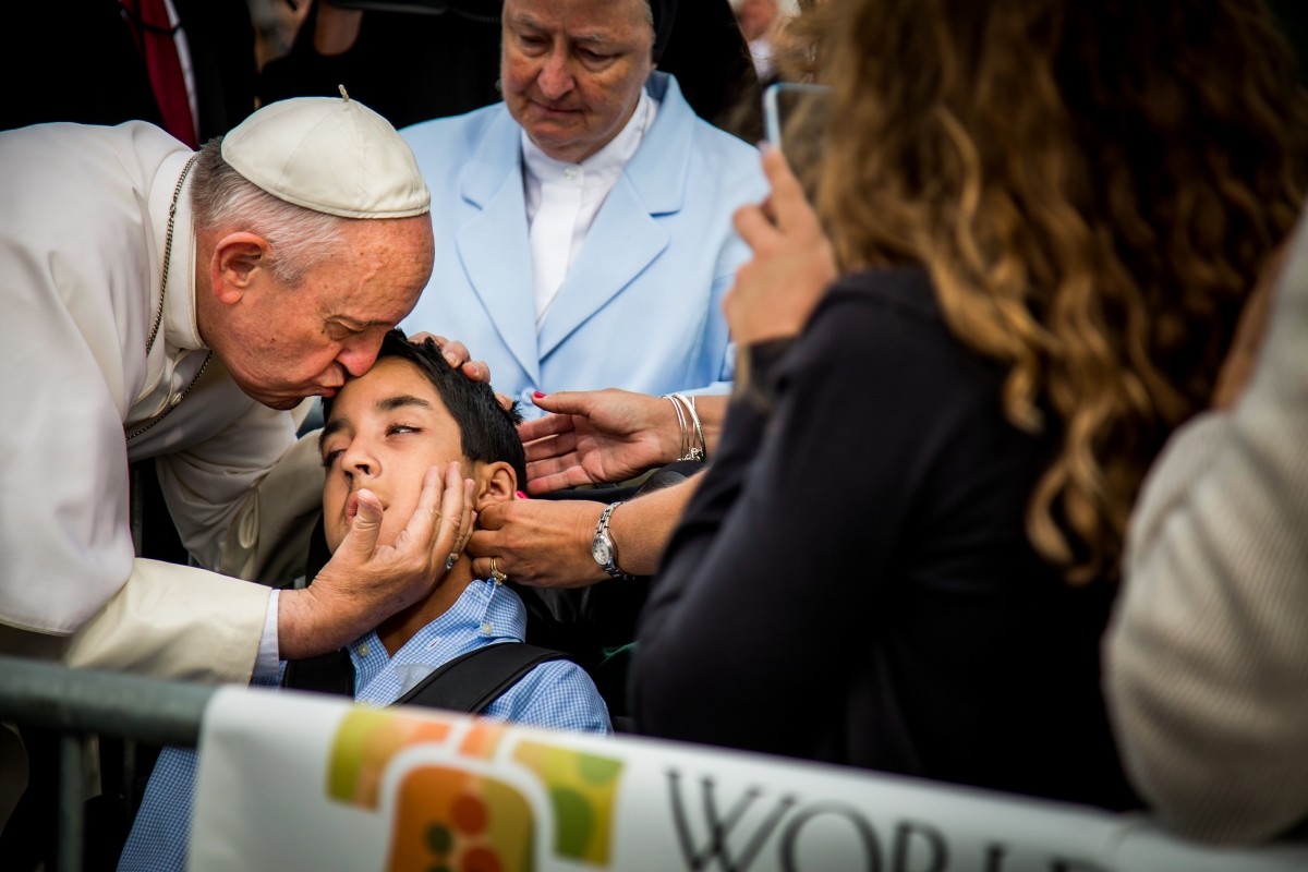 Pope Francis kissing Michael Keating, a young boy with cerebral palsy, on the forehead