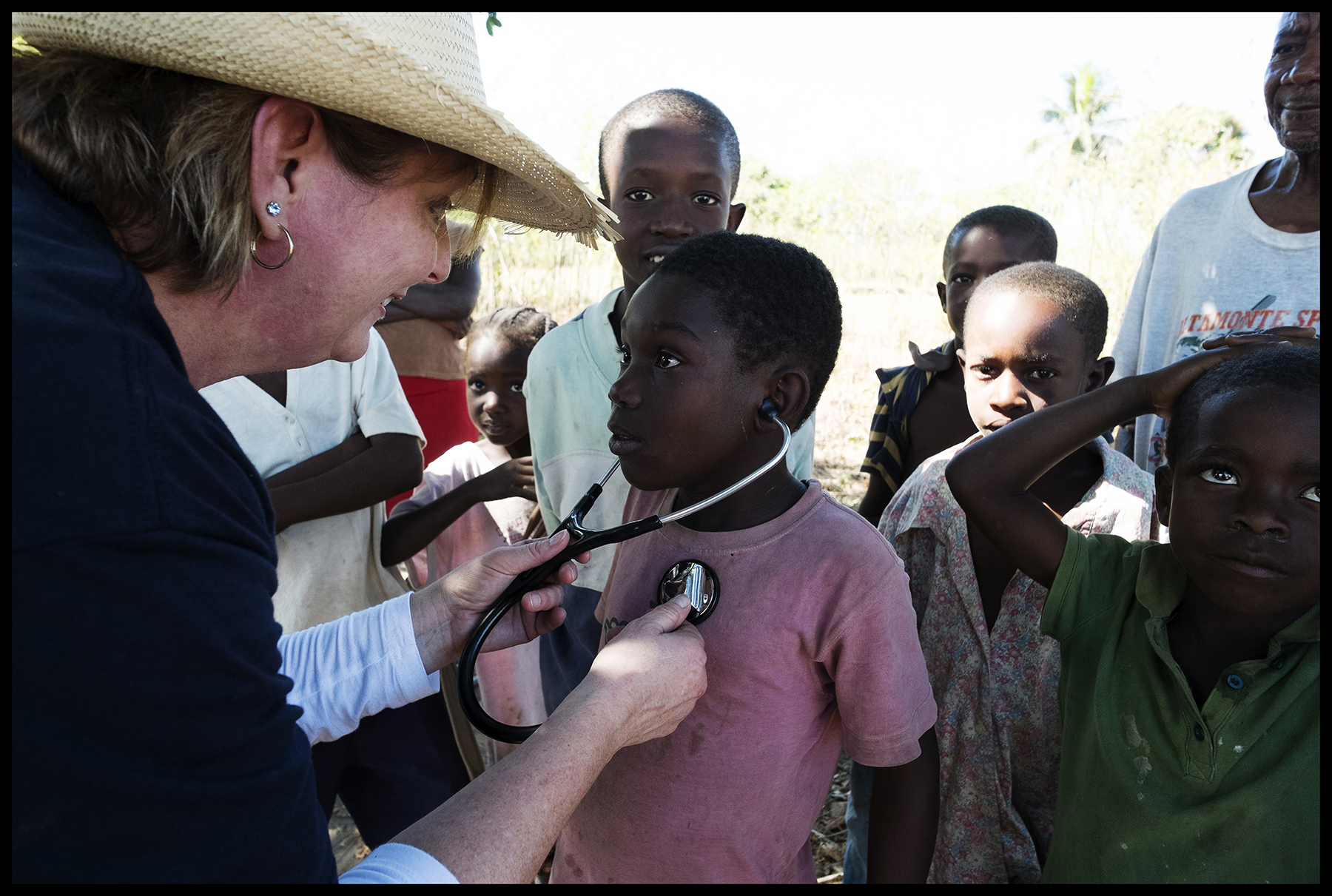 Woman holding stethoscope up to child