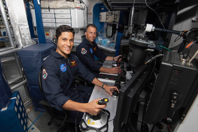 Mounir Alafrangy (left) works at the piloting station. (NASA)