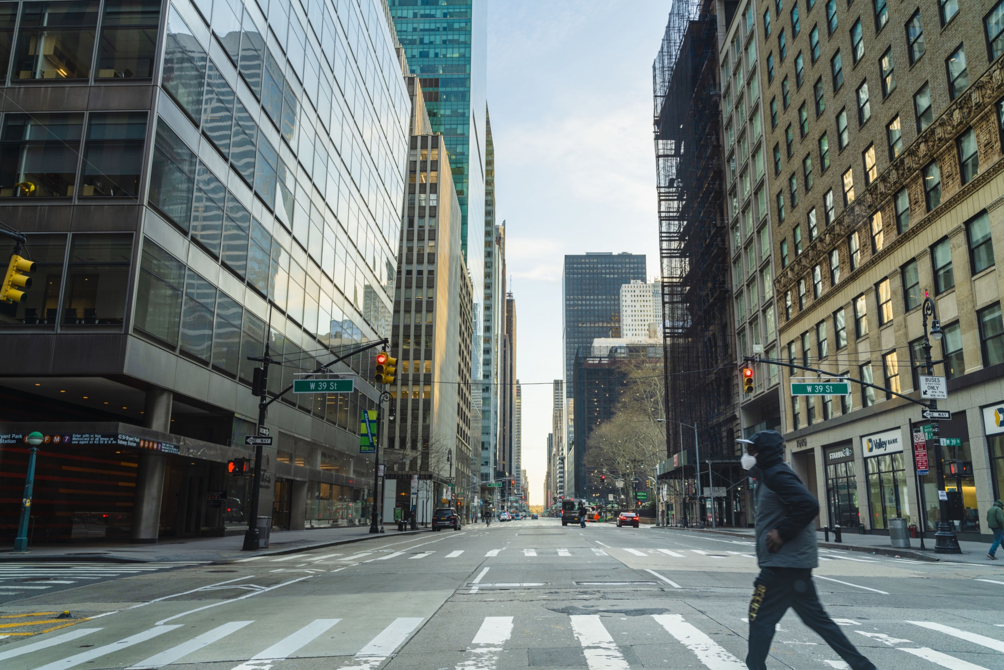Masked person crossing a nearly empty street in downtown NYC