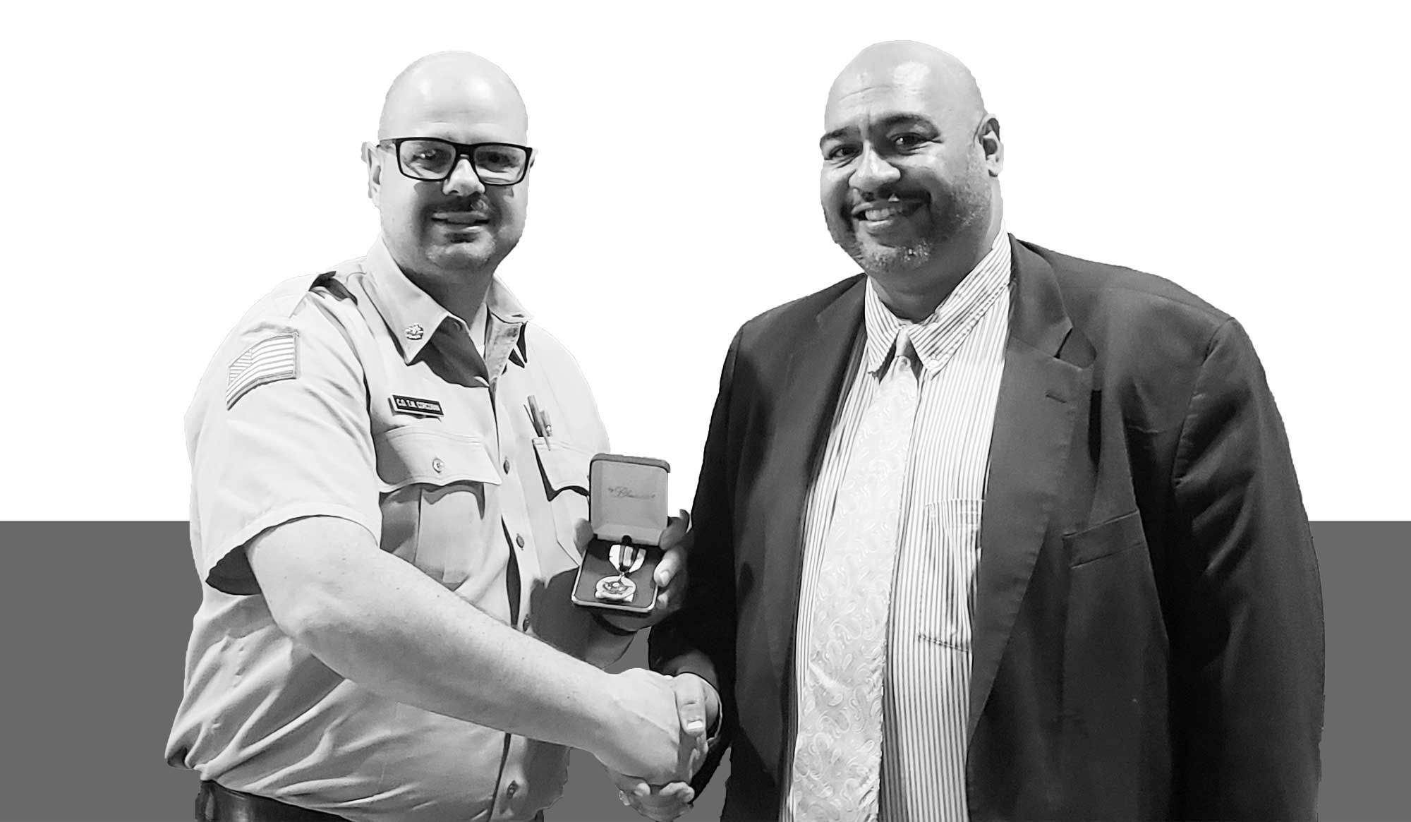 Two men shaking hands holding a metal