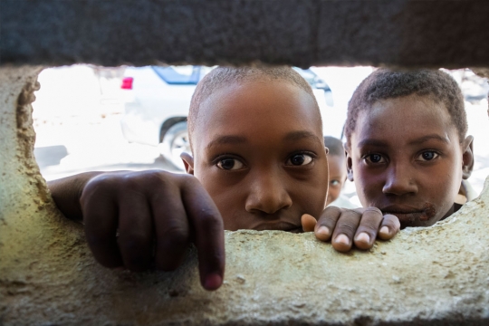 Children looking through a space in a wall