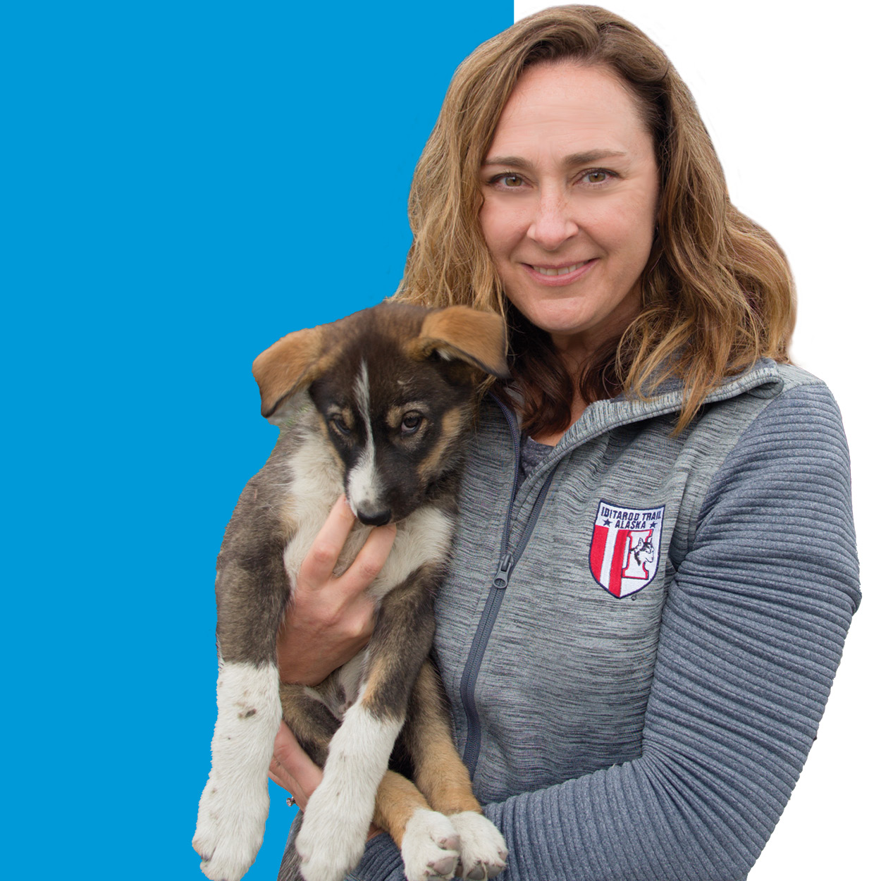 Juli Westrich holding a dog with a blue background