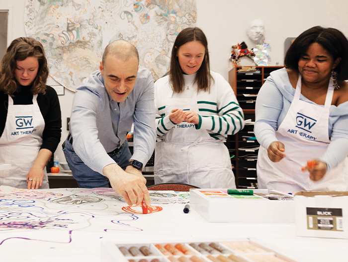 Ulvi Kasimov with three students wearing aprons participating in an art project