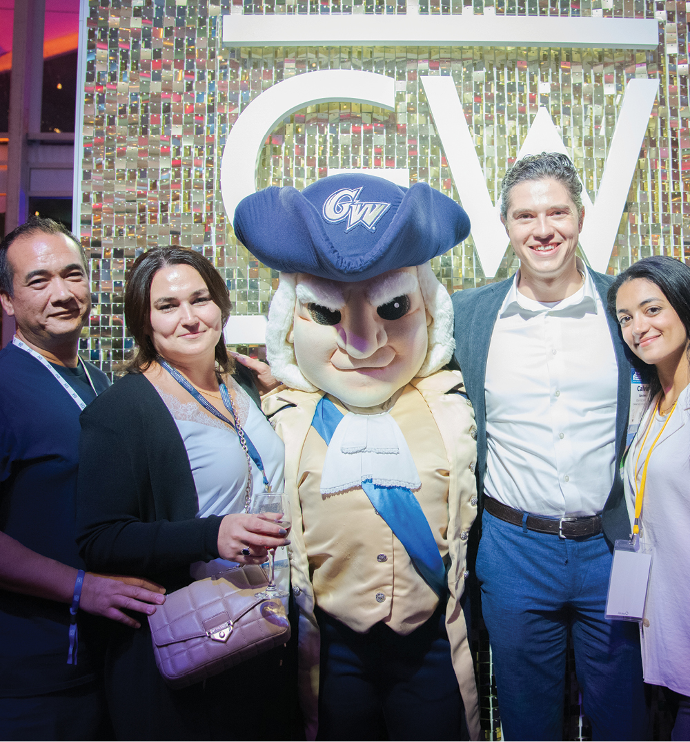 4 alumni pose with George mascot