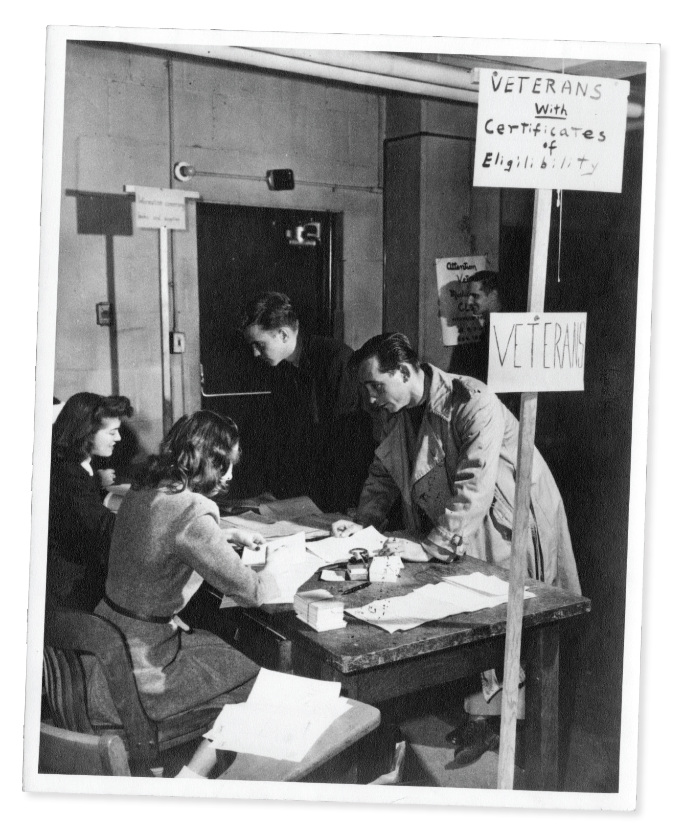 black and white photo of a man submitting his veterans certificate of eligibility at a table of 2 women