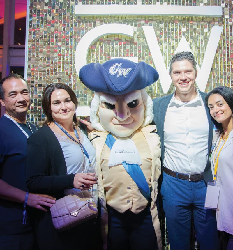 4 alumni pose with George mascot