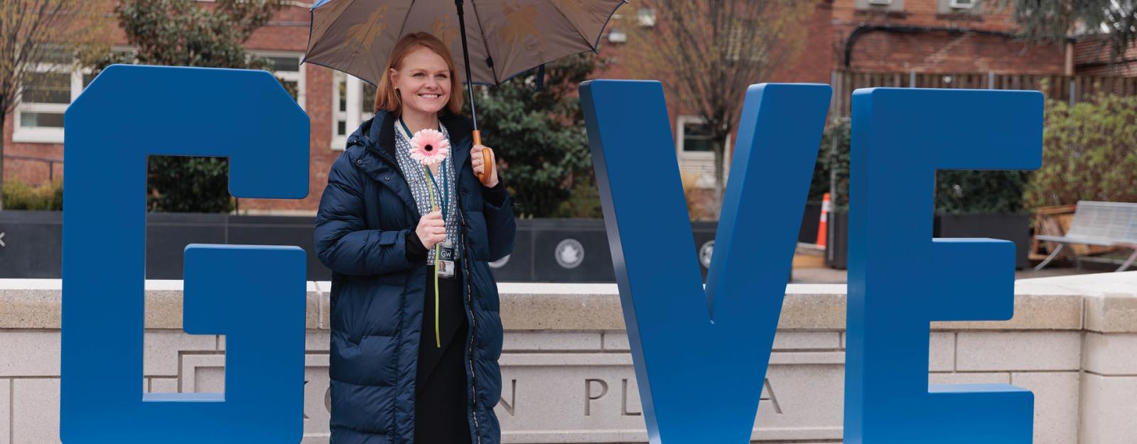 Student standing in as the "I" letter in a giant G-I-V-E installment