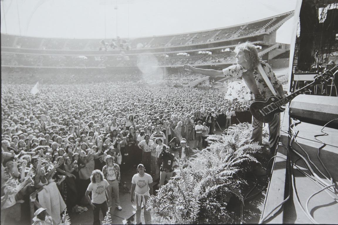 Peter Frampton leaning off the stage at a concert in candlestick park