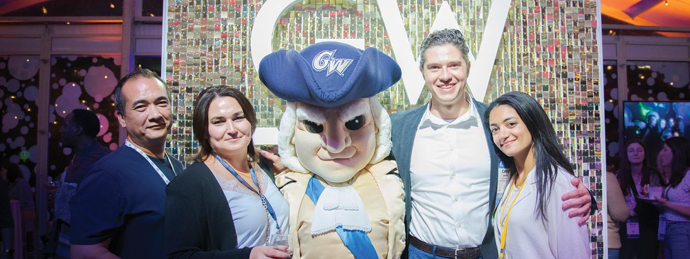 Four people pose for a photo with the George Washington mascot during Alumni & Families Weekend